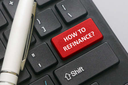 Selective focus of a pen and keyboard with red button written with question of How to refinance?....