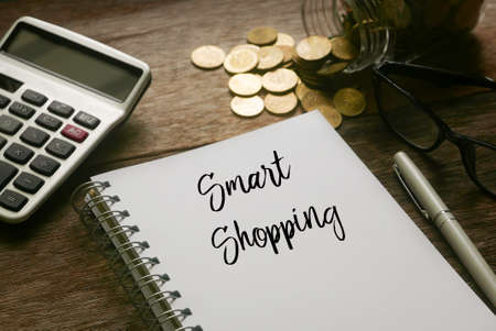 Selective focus of calculator,gold coins,pen,glasses and notebook written with Smart shopping on...