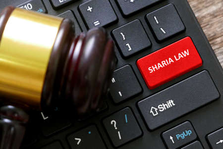Selective focus of a gavel and a keyboard with red button written with Sharia Law.