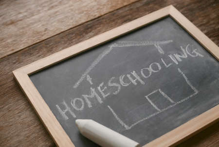 Selective focus of a chalkboard written with Homeschooling on wooden background.の写真素材