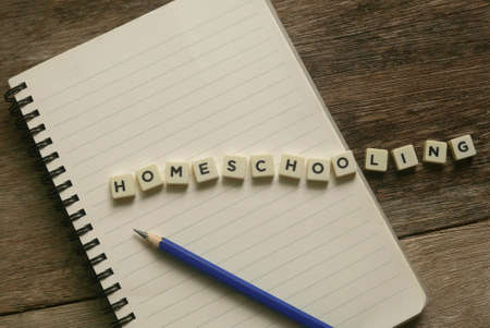 Top view of notebook,pencil and cube alphabet of word Homeschooling on wooden background.の写真素材