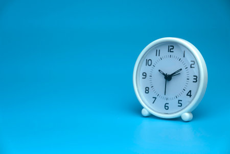 Selective focus of white table clock isolated on a blue background with a copy space.の写真素材