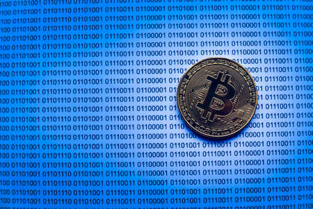 Selective focus of gold bitcoin on a paper of binary code.の写真素材