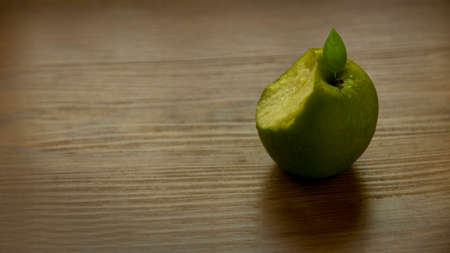 Green, juicy apple bite on wooden background woth copy space.の写真素材
