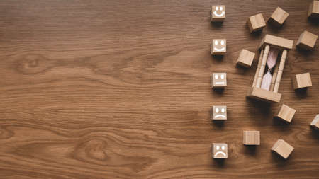 Top view of sand clock and wooden cube with face expression of rating on wooden background with copy space. Customer experience concept.の写真素材