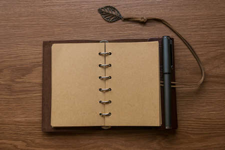 Top view of vintage notebook and pen on wooden background.
