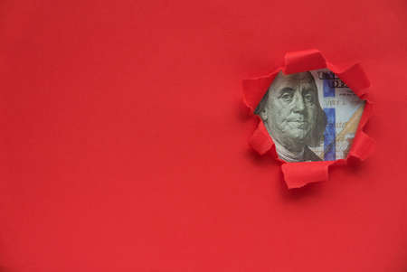 Portrait of Benjamin Franklin on a dollar bill of a red torn paper with copy space.の写真素材
