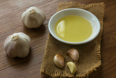 Selective focus of garlic and its oil on wooden background.の写真素材