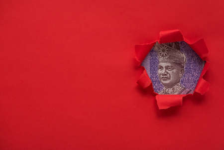 Portrait of Almarhum Tuanku Abdul Rahman ibni Almarhum Tuanku Muhammad on a Ringgit bill of a red torn paper with copy space.の写真素材