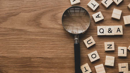 Q&A or questions and answers concept with wooden alphabet and magnifying glass on wooden background...