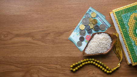 Concept of zakat in Islam religion. Top view of money, rice, Koran and prayer beads on wooden background with copy space.の写真素材