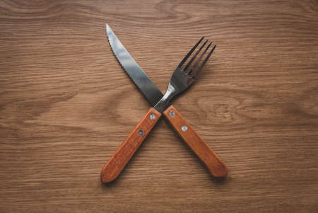 Food concept.Top view of crossing knife, spoon on wooden table.の写真素材