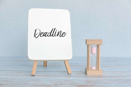 Concept of deadline and time with sand clock and white board written with Deadline.の写真素材