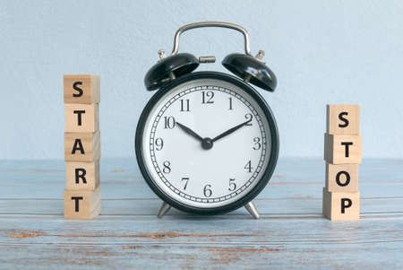A stack of wooden cube of word START and STOP with vintage alarm clock.の写真素材