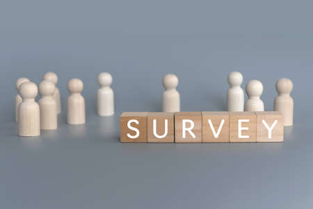 Selective focus of wooden people with a wooden cube written with Survey on gray background.の写真素材