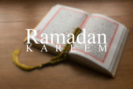 Phrase of Ramadan Kareem with blurry background of Quran and Rosary beads.の写真素材
