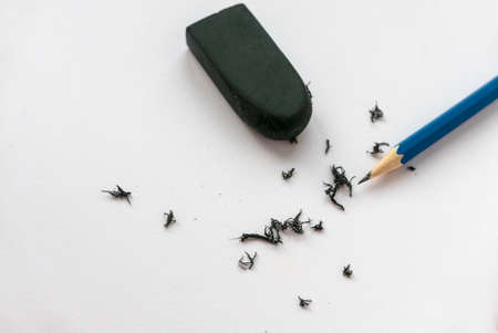 Blue pencil, black eraser and its scrap on white paper background.の写真素材