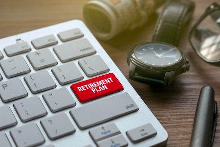 Retirement and pension concept with money, watch,glasses, pen and keyboard with red button written...