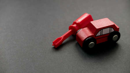 Car maintenance, car service or car repair concept. A toy car and screwdriver on a black background with copy space.の写真素材