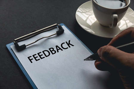 A man writing on a clipboard with paper written with Feedback.の写真素材