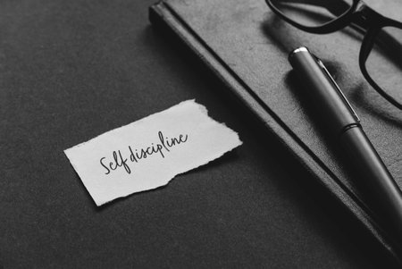 Selective focus of glasses,pen, notebook and a piece of paper written with Self Discipline.の写真素材