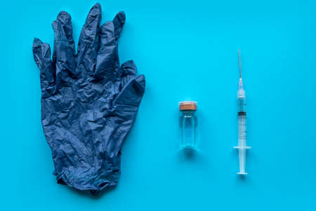 Top view of blue glove, syringe and a bottle of vaccine on a blue backgroundの写真素材