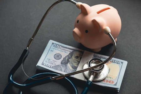 A piggy bank checking money using stethoscope on a black background.の写真素材