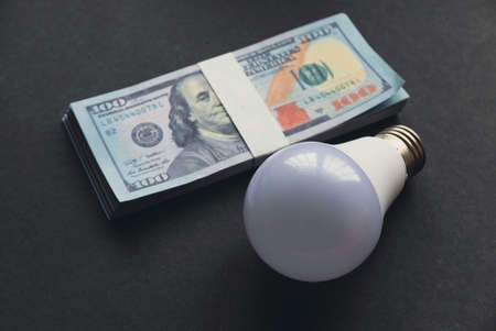 A bulb and money on a black background.の写真素材