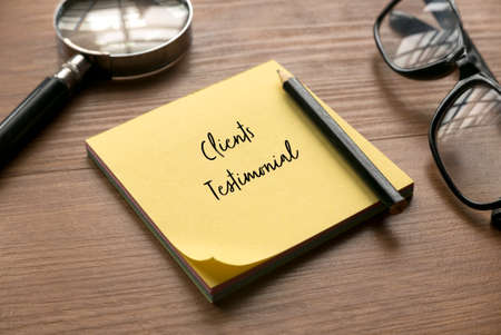 Selective focus of magnifying glass, glasses, pencil and yellow memo note written with Clients Testimonial.の写真素材