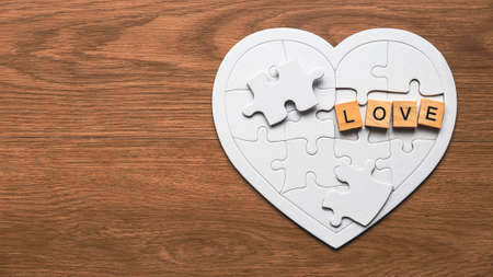 Top view of heart shape jigsaw puzzle and wooden alphabet of word love on wooden background.の写真素材