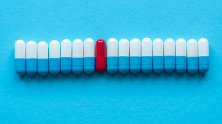 A row of medicine pills with a single red pill in the middle.の写真素材