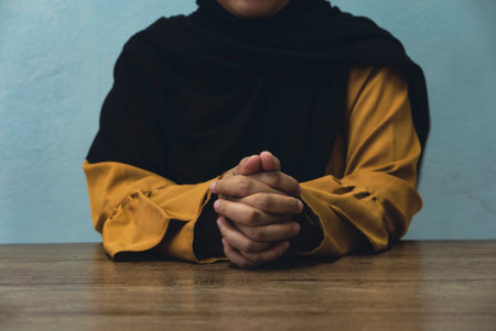 A hijabi women hold his hand on a table.の写真素材
