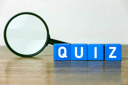 A magnifying glass and a blue wooden cube written with QUIZ on a table.の写真素材