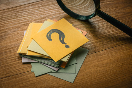 Questions and answers concept. A stack of paper with a paper on top written with question symbol together with magnifying glasses.の写真素材