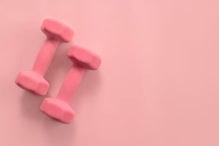 Fitness and healthy sport concept. Pink dumbbell on a pastel pink background. Top view, flat lay, copy spaceの写真素材