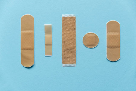 Different kind of shape and size of adhesive bandage elastic medical plasters isolated on blue background.の写真素材