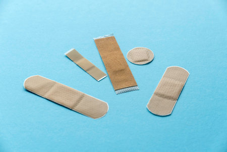 Different kind of shape and size of adhesive bandage elastic medical plasters isolated on blue background.の写真素材