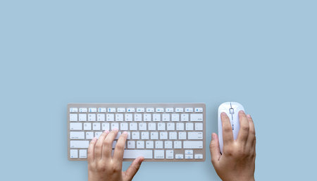 Person using computer from above. Office desktop. Blue background. Copy space.の写真素材