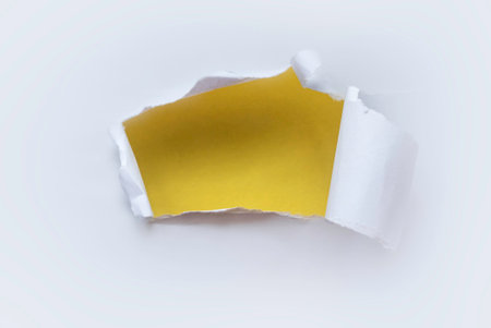 A hole of paper ripped and torn. Reveal a yellow wall behind. Backdrop or background.の写真素材
