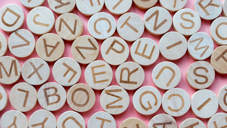 Circle wooden alphabet over a pink background.