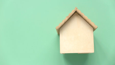 Environmentally friendly house concept. Eco home and real estate. Wooden house model over a green background. Copy space.の写真素材