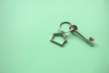 Environmentally friendly house concept. Eco home and real estate. House key over a green background. Copy space.の写真素材