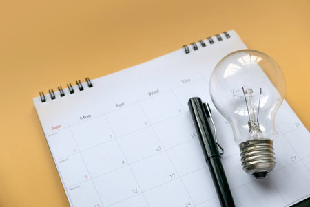 Creativity inspiration concepts, planning ideas. Bulb and calendar on yellow background.の写真素材