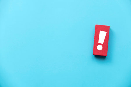 Exclamation mark on red wooden rectangular isolated on blue background. Copy space.の写真素材