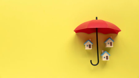 Concept of renters home  or mortgage protection. House under a red umbrella on yellow background with copy space.の写真素材