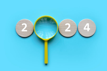 New year concept. Magnifying glass with a wooden circle with number over a blue background.