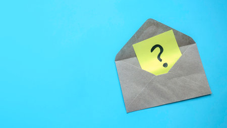 Q&A or questions and answers concept. Question mark on a paper in an envelope. Blue background with copy space.の写真素材