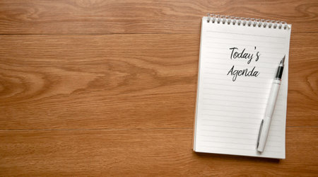 Top view of pen and notebook written with Today's Agenda on wooden background with copy space.