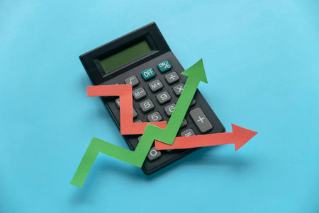 red and green arrow graph on calculator over a blue background.の写真素材