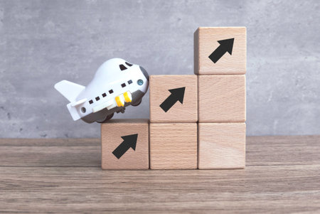 Toy Plane, Arrow Up, and Wooden Cube Symbolizing Growth and Progressの写真素材